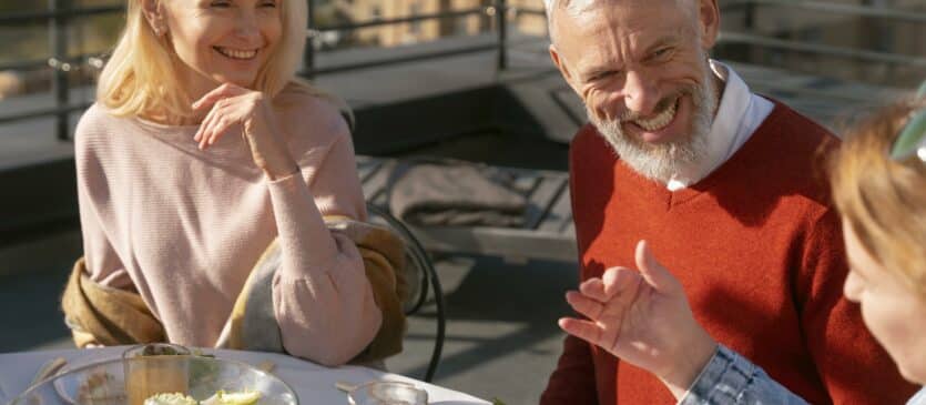 Older couple laughing with friends on a sunny patio